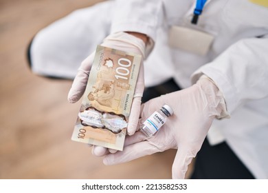 Young Caucasian Woman Scientist Holding Canada Dollar Banknote And Covid Dose Vaccine At Laboratory