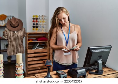 Young Caucasian Woman Shopkeeper Counting Dollars Working At Clothing Store