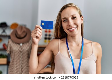 Young Caucasian Woman Shopkeeper Holding Credit Card Working At Clothing Store