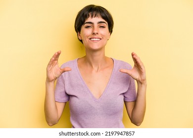 Young Caucasian Woman With A Short Hair Cut Isolated Holding Something With Palms, Offering To Camera.