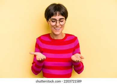 Young Caucasian Woman With A Short Hair Cut Isolated Holding Something With Palms, Offering To Camera.