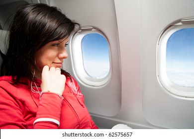 Young Caucasian Woman Is Sitting In The Airplane And Dreaming