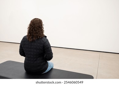 Young Caucasian Woman Sitting on a Bench in a Minimalist Room, Contemplating - Powered by Shutterstock