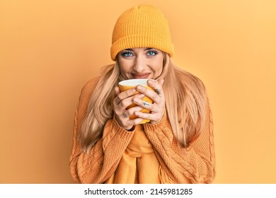 Young Caucasian Woman Smelling Coffee Aroma Over Yellow Background