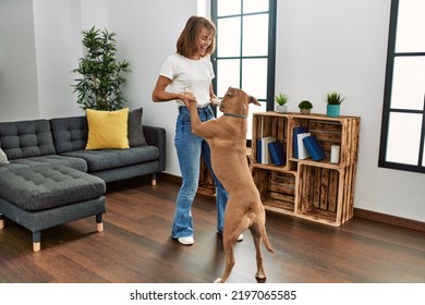 Young caucasian woman smiling confident dancing with dog at home - Powered by Shutterstock