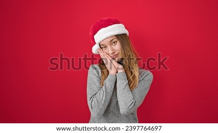 Young caucasian woman smiling confident wearing christmas hat over isolated red background