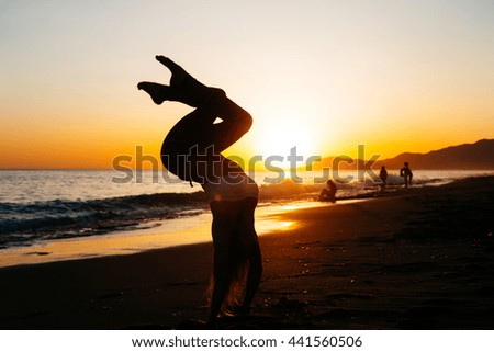 Young caucasian woman standing on her hands at the beach of mediterranean sea