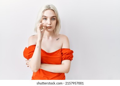 Young caucasian woman standing over isolated background mouth and lips shut as zip with fingers. secret and silent, taboo talking 
