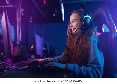 Young caucasian woman streaming video games with enthusiasm in neon lit gaming setup.