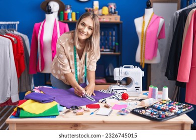 Young caucasian woman tailor cutting cloth at sewing studio - Powered by Shutterstock