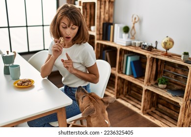 Young caucasian woman teaching dog prohibition eat cookies at home - Shutterstock ID 2236325405