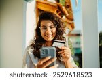 Young caucasian woman using credit card to buy online on her phone	