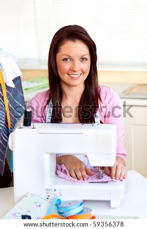 Young caucasian woman using a sewing-machine in the kitchen at home