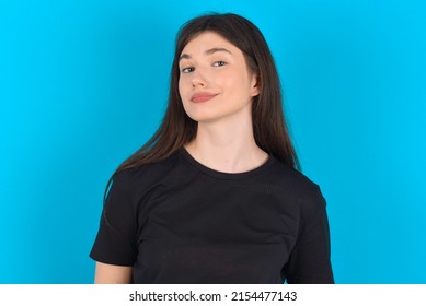 Young Caucasian Woman Wearing Black T-shirt Over Blue Background With Snobbish Expression Curving Lips And Raising Eyebrows, Looking With Doubtful And Skeptical Expression, Suspect And Doubt.