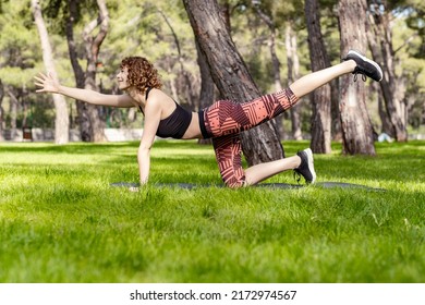 Young Caucasian Woman Wearing Black Sports Bra Standing On City Park, Outdoor Doing Donkey, Kick Exercise, Bird Dog Pose, Working Out, Concept Of Healthy Lifestyle, Yoga.