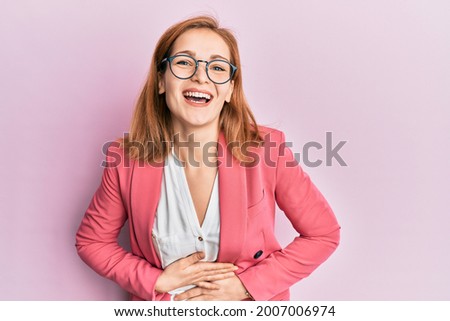Young caucasian woman wearing business style and glasses smiling and laughing hard out loud because funny crazy joke with hands on body. 