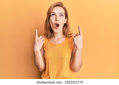 Young Caucasian Woman Wearing Casual Style With Sleeveless Shirt Amazed And Surprised Looking Up And Pointing With Fingers And Raised Arms. 