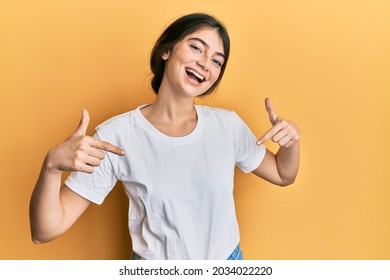 Young caucasian woman wearing casual white t shirt looking confident with smile on face, pointing oneself with fingers proud and happy. 
