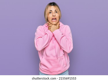 Young caucasian woman wearing casual sweatshirt shouting and suffocate because painful strangle. health problem. asphyxiate and suicide concept. 