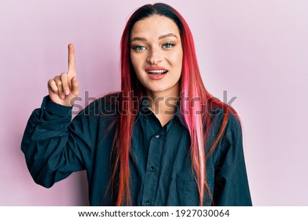 Young caucasian woman wearing casual clothes smiling with an idea or question pointing finger up with happy face, number one 