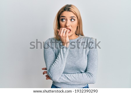 Young caucasian woman wearing casual clothes looking stressed and nervous with hands on mouth biting nails. anxiety problem. 