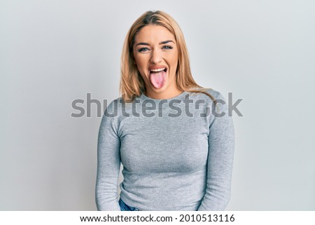 Young caucasian woman wearing casual clothes sticking tongue out happy with funny expression. emotion concept. 