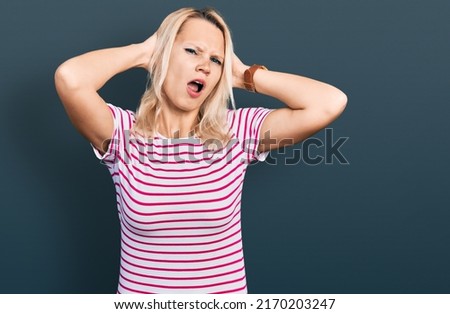 Young caucasian woman wearing casual clothes crazy and scared with hands on head, afraid and surprised of shock with open mouth 