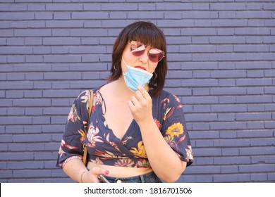 Young caucasian woman wearing face mask wrongly and wanting to remove her mask. Coronavirus prevention concept. - Powered by Shutterstock