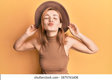 Young caucasian woman wearing hat looking at the camera blowing a kiss being lovely and sexy. love expression. 