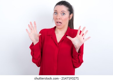 young caucasian woman wearing red shirt over white background afraid and terrified with fear expression stop gesture with hands, shouting in shock. Panic concept.