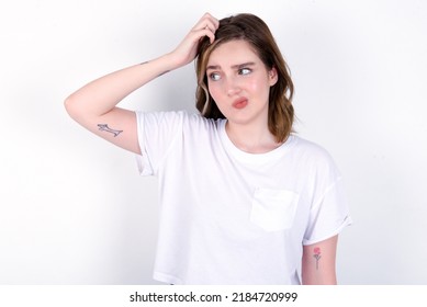 Young Caucasian Woman Wearing White T-shirt Over White Background Saying: Oops, What Did I Do? Holding Hand On Head With Frightened And Regret Expression.