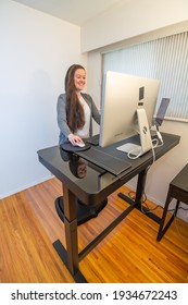 A Young Caucasian Woman Working At Her Ergonomic Desk, Half Dressed. Standing On A Mat