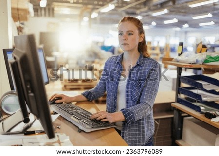 Young Caucasian woman working on a computer in a warehouse