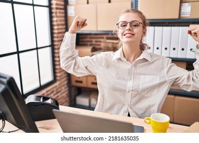 Young Caucasian Woman Working At Small Business Ecommerce Using Laptop Showing Arms Muscles Smiling Proud. Fitness Concept. 