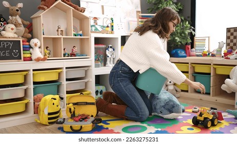 Young caucasian woman working as teacher tidying up at kindergarten - Shutterstock ID 2263275231
