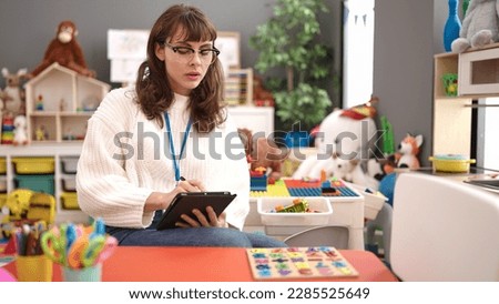 Young caucasian woman working as teacher with tablet at kindergarten