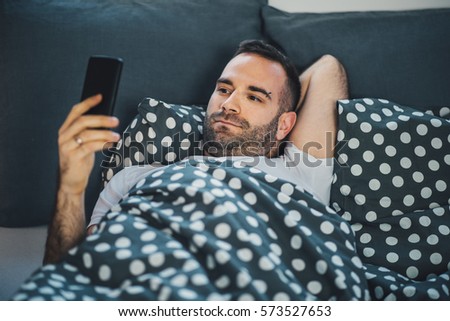 Similar – Image, Stock Photo Phone addiction. Man lying in bed with smartphone