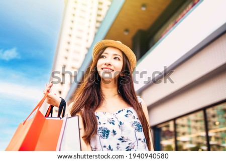 young charming asian woman holding shopping bags on the street