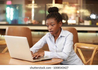 Young charming black girl looking interested while watching laptop at table.  - Shutterstock ID 1008543427
