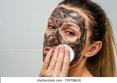 Young charming girl makes a black charcoal mask on her face