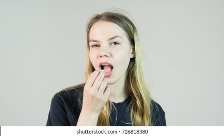 Young Charming Smiling Woman Puts In Mouth Chewing Gum On White Background