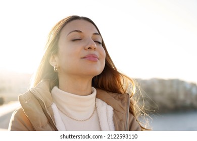 Young charming woman breathing fresh air relaxing and smiling with closed eyes at sunset