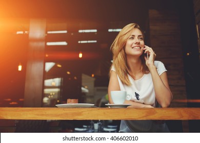 Young charming woman calling with cell telephone while sitting alone in coffee shop during free time, attractive female with cute smile having talking conversation with mobile phone while rest in cafe - Shutterstock ID 406602010