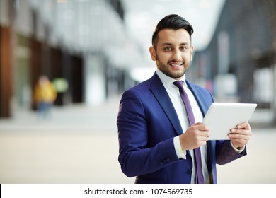 Young cheerful businessman with tablet looking at camera while analyzing online dat in airport lounge - Shutterstock ID 1074569735