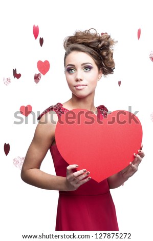 young cheerful caucasian brunette woman in red dress holding big red paper heart
