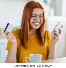 Young cheerful caucasian woman using bank credit card and mobile phone to shopping online on the internet, redhead beautiful excited girl feels euphoria from long-awaited purchase the Internet - Shutterstock ID 2192546599