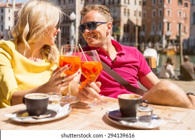 Young Cheerful Couple Drinking Aperol Spritz Cocktail In Cafe