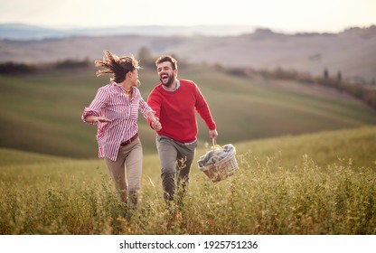 A young cheerful couple enjoying running over a large meadow while holding by hands on a beautiful sunny day. Love, relationship, together, nature - Powered by Shutterstock