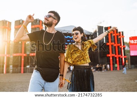 Young and cheerful couple at music festival. Happy friends drinking beer and having fun at Beach party together. Summer holiday, vacation concept.