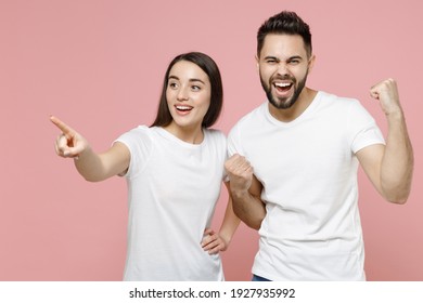 Young cheerful couple two friends man woman in white basic blank print design t-shirts doing winner gesture celebrating clenching fists say yes isolated on pastel pink color background studio portrait - Shutterstock ID 1927935992